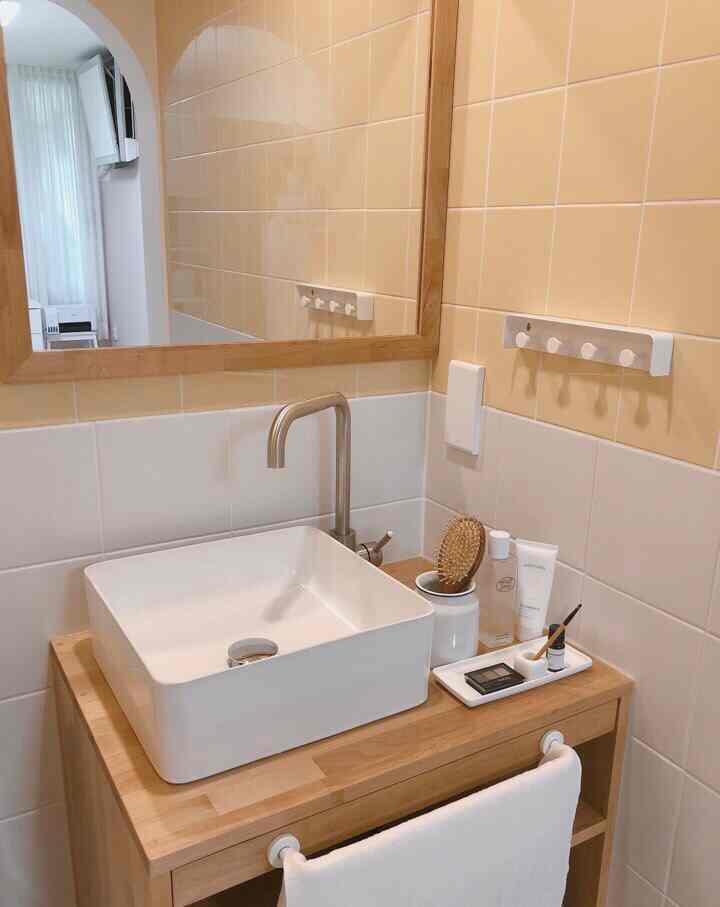 Natural-toned bathroom featuring wood tone shelf and white square sink in a clean, minimal space
