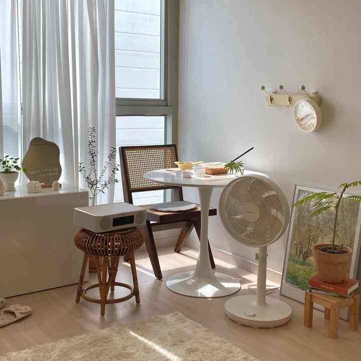 Small two-person dining room in white and brown tones, featuring a round table and rattan chair with a calm atmosphere