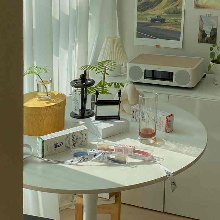 Bright white and natural toned dining space featuring a round table with coffee accessories and audio device, cozy atmosphere