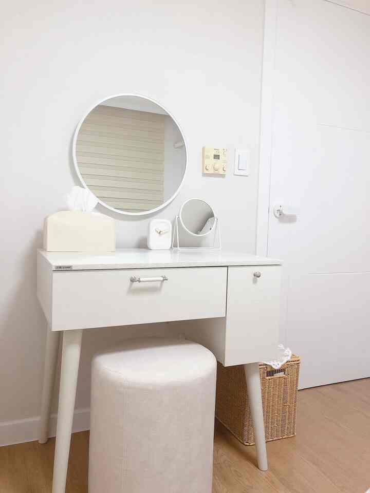ホワイトとナチュラルトーンの化粧台が配置されたシンプルで清潔感のある寝室とリビング空間