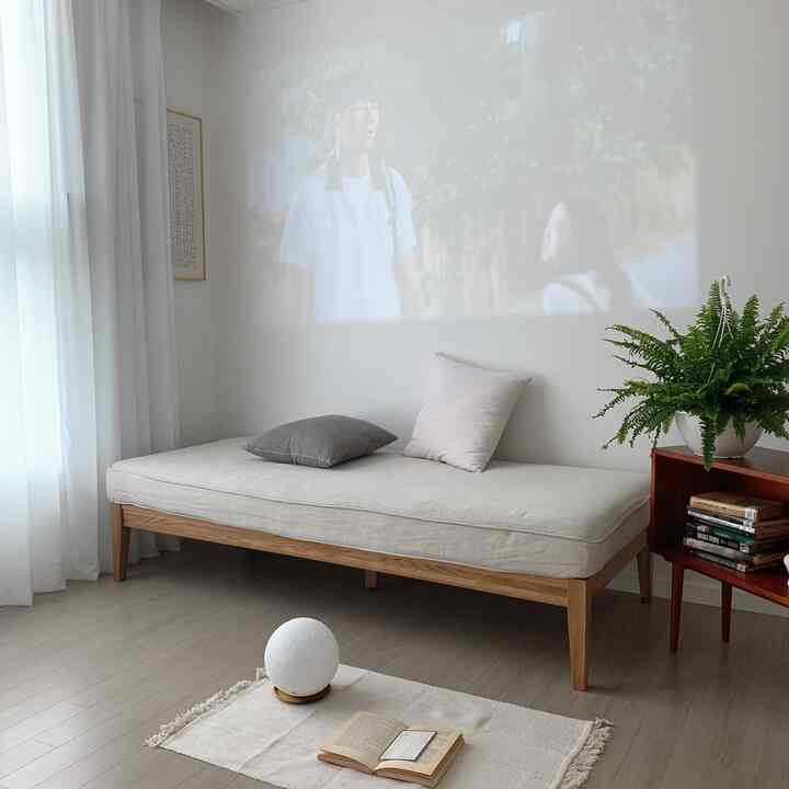 ホワイトとウッドトーンが調和したリビング、シンプルなデイベッドと植物が配置された落ち着いた空間