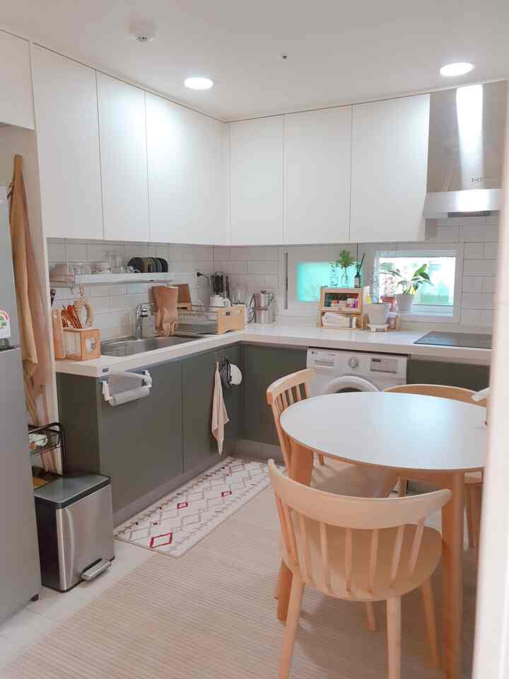 Cozy small kitchen featuring white and natural wood tones, with round dining table and chairs arranged warmly
