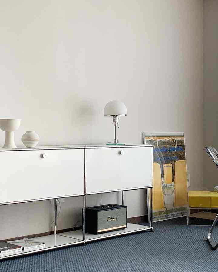 Modern living room with white walls, USM storage cabinet, Marshall speaker, and blue carpet