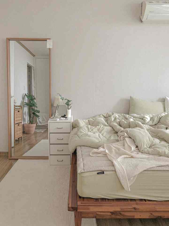 Beige and wood-tone bedroom featuring a wooden bed, white nightstand, and a full-length mirror in a natural modern style space