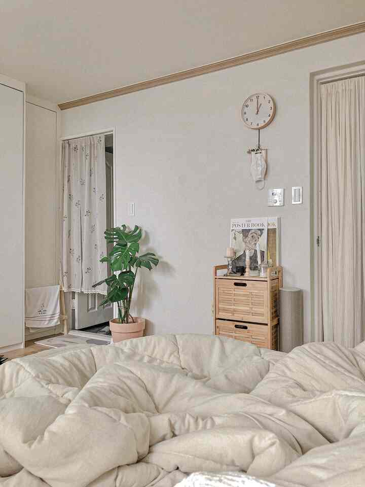 Natural style room with light beige walls and bedding, showing a restroom entrance with curtain