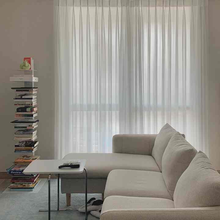 White and natural toned living room featuring a compact bookshelf and beige sofa for a minimal atmosphere