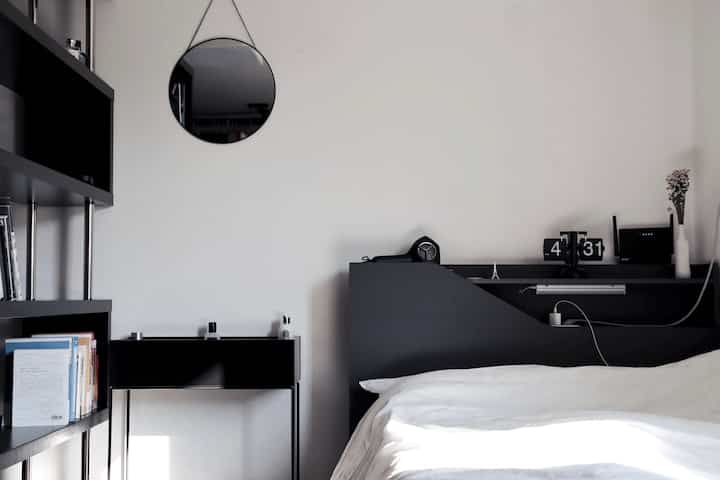 White walls and black furniture harmonize in this studio bedroom, featuring a minimal and modern aesthetic