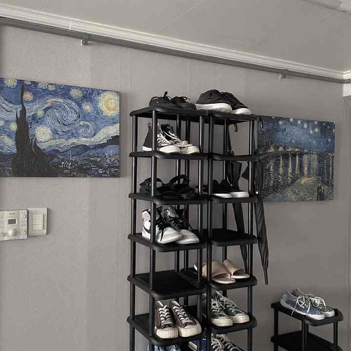 Black-toned entrance area featuring Van Gogh picture frames and a shoe cabinet, creating a clean and modern atmosphere