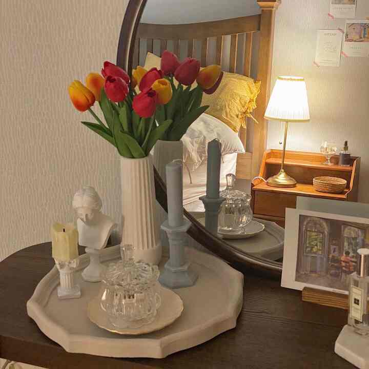 Cozy bedroom vanity with warm wood tones and vibrant red tulips as focal point, complemented by neat accessories and soft lighting