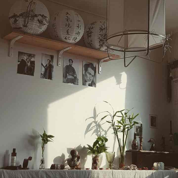 温かみのある白い壁と緑の植物が配置されたアジアン風の寝室脇の雰囲気ある飾り棚スペース