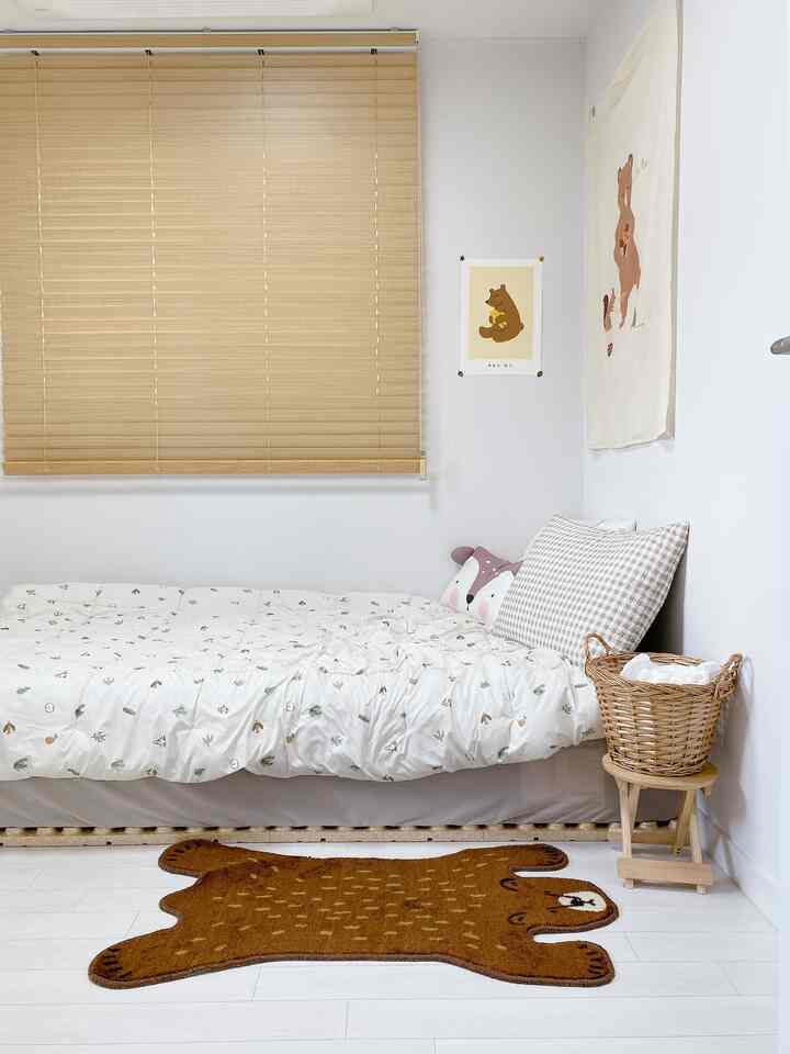 白い壁と茶色の木製ブラインド、子供用ベッドと動物モチーフの飾りがある温かみのある子供部屋のインテリア