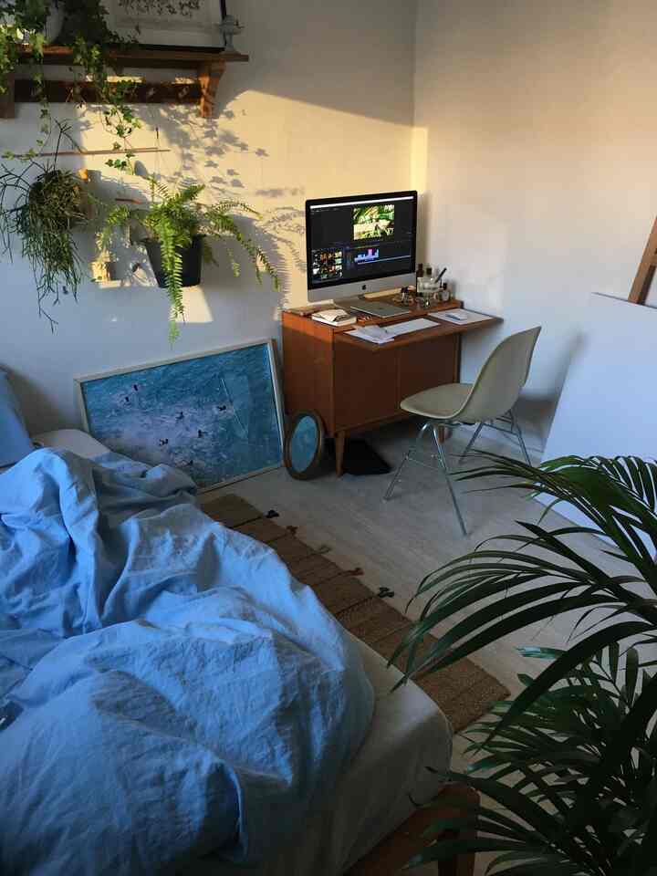 White-toned bedroom with blue bedding featuring a compact wooden desk and computer creating a cozy home office space