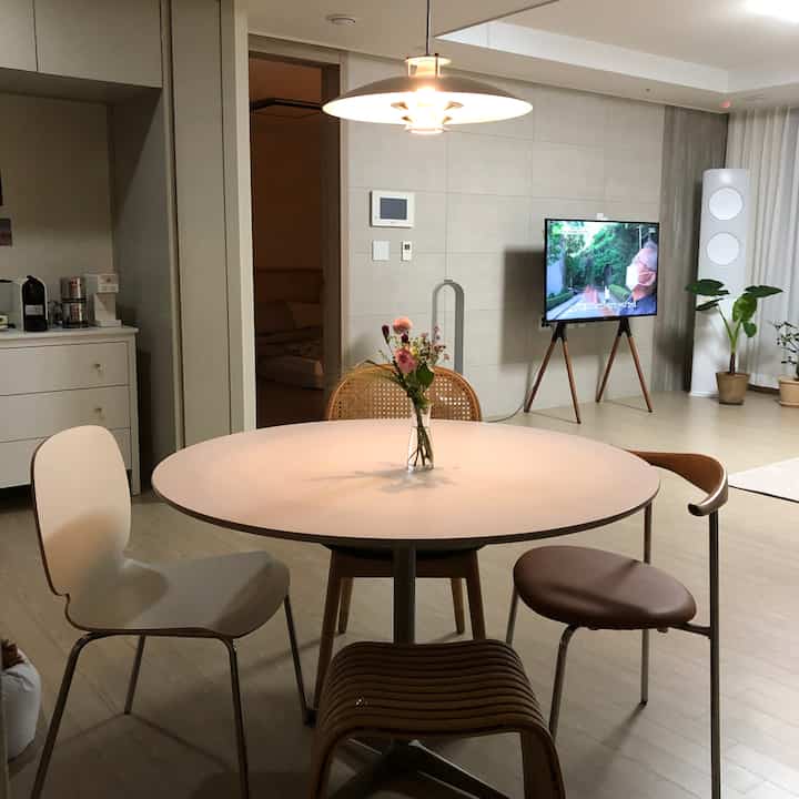 Natural tone studio living room featuring a round dining table and varied chairs in a cozy home cafe setup