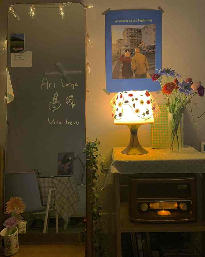 Vintage studio room at night with warm table lamp and floral decor, poster on wall adds character
