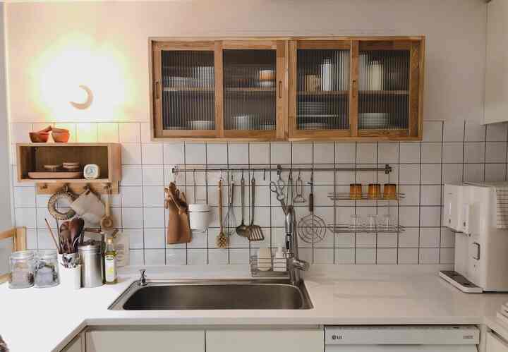 White and wood tone kitchen featuring neat storage solutions and a natural, clean atmosphere