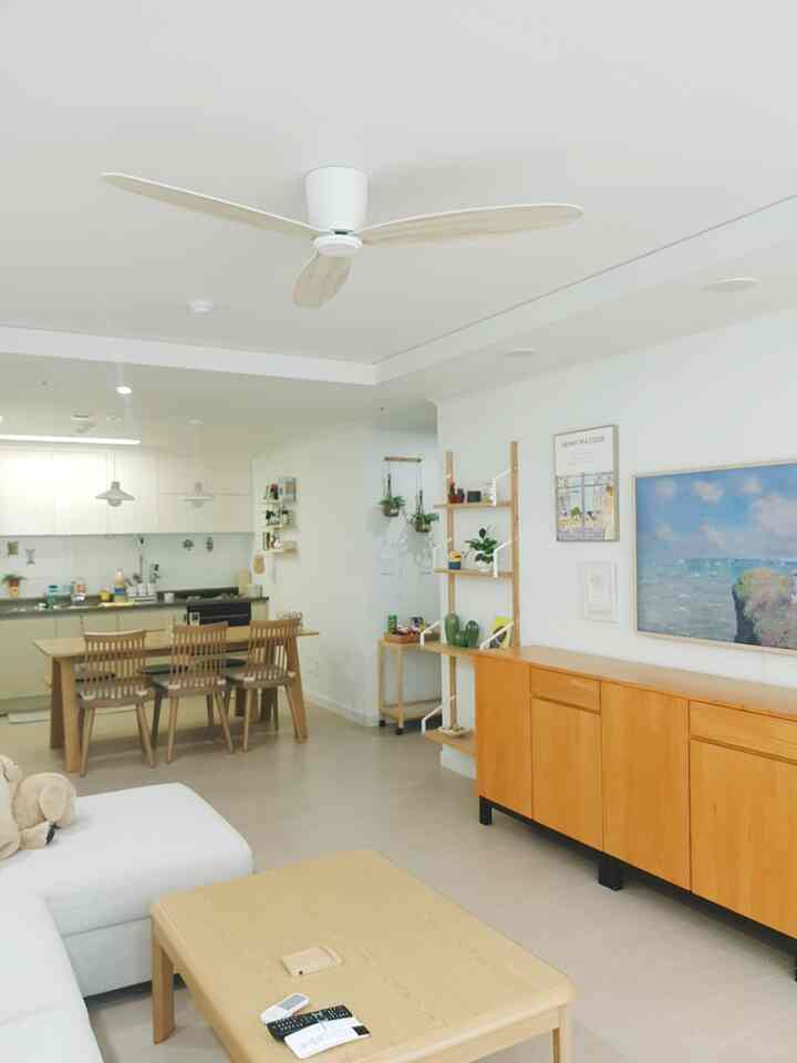 白と木目調の色合いが調和するリビングとキッチン、6人用ダイニングテーブルとシーリングファンがある明るくナチュラルな空間