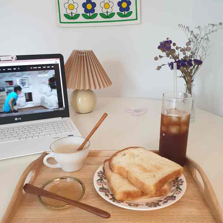 Simple kitchen space with white walls and round table, wood tone tray holding drip coffee, toast creating a cozy home cafe vibe