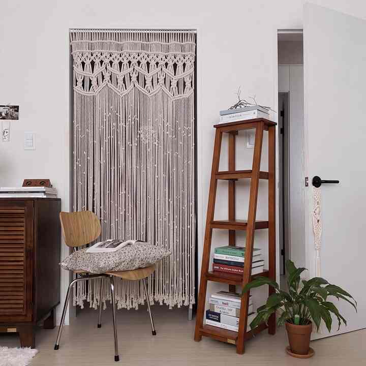 White and brown toned bedroom featuring a tall ladder plant stand and a potted plant in a cozy natural setting