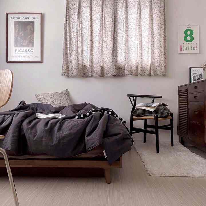 Natural wood tones and white hues blend in a bedroom featuring a wooden bed and armchair, creating a simple and modern space