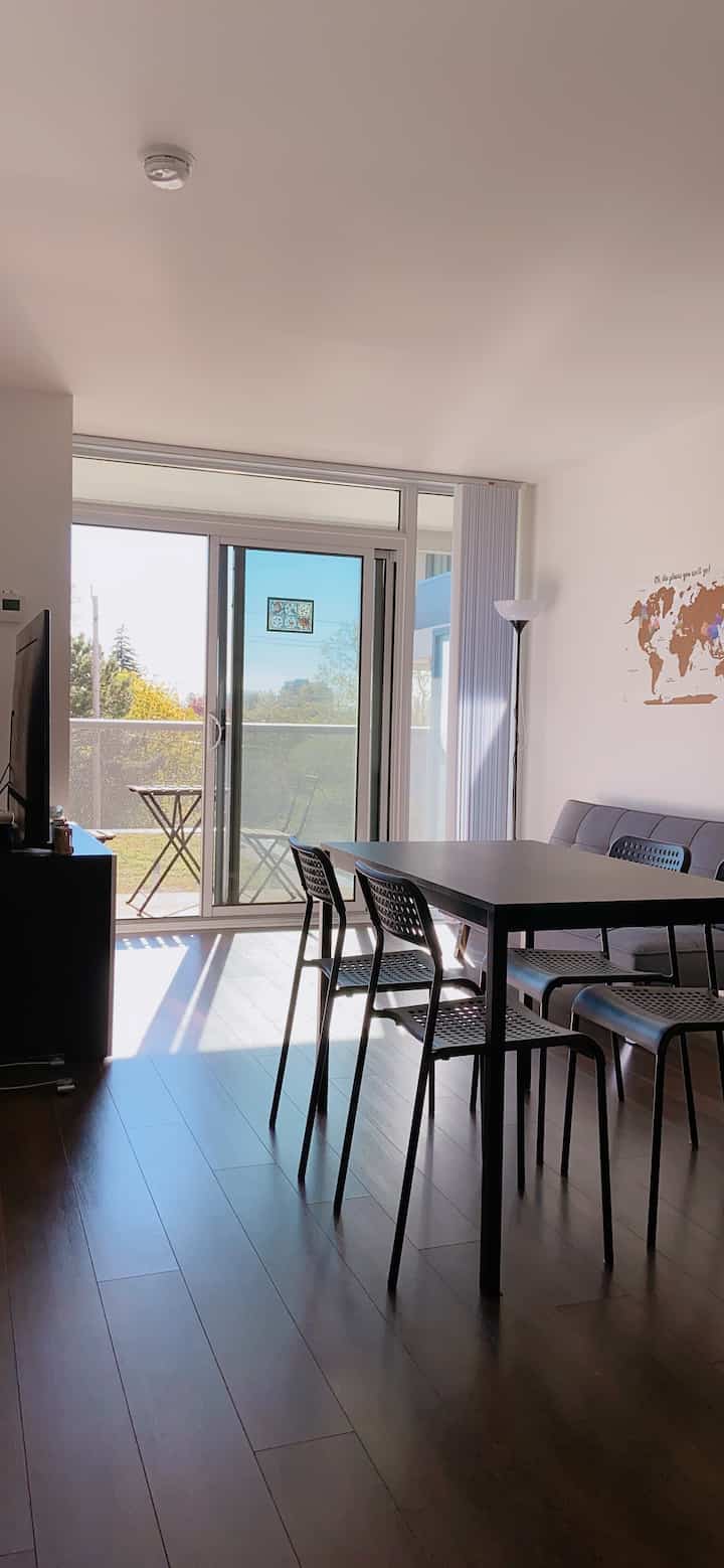 A simple modern living room with white walls, brown wood-tone floor, and dining table with chairs