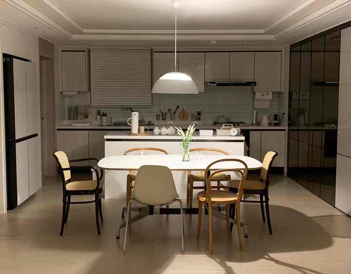 Clean kitchen with white and wood tones, featuring a cozy AJ Royal pendant light above the central dining table
