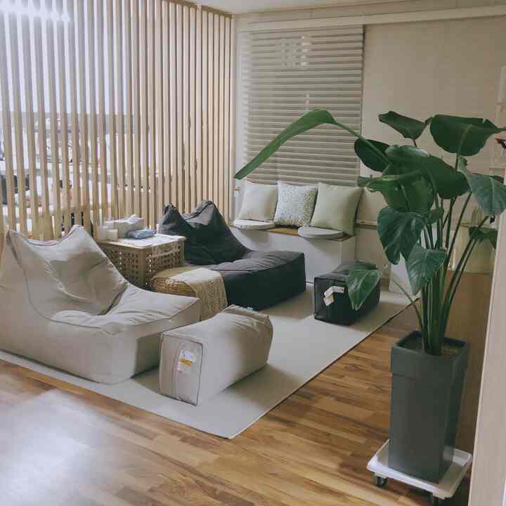 Beige and wood-toned living room featuring bean bags and a wooden partition, creating a cozy home cafe style interior