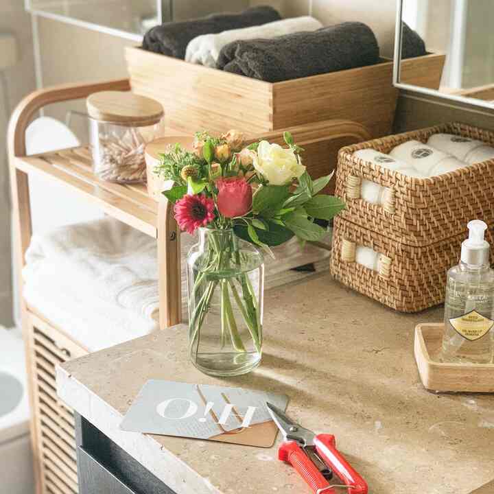 Natural wood-toned bathroom storage space with a transparent vase of flowers, creating a clean and warm atmosphere