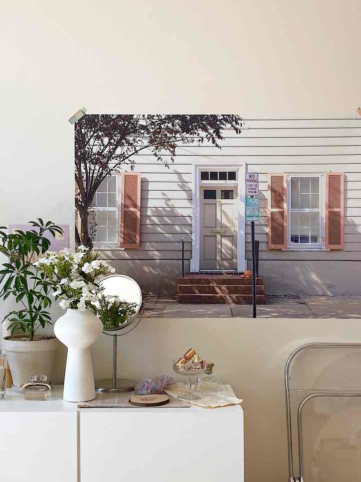 White-toned room featuring a large poster, vanity, and plants with a clean, natural interior atmosphere