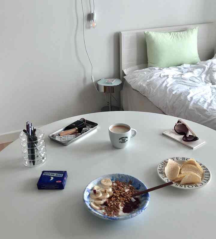 White-toned bedroom with a round table and bed, featuring a modern and clean interior