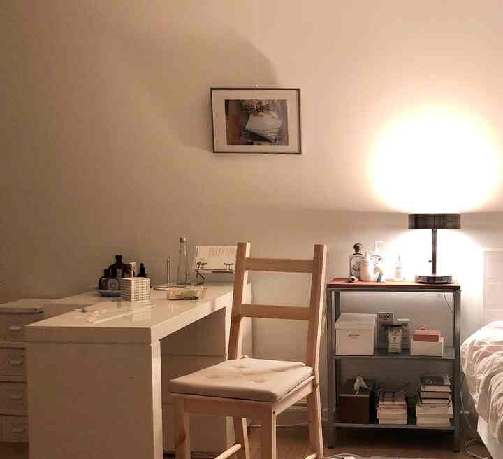 Warm white and natural toned bedroom featuring wood chair and table lamp creating a cozy atmosphere