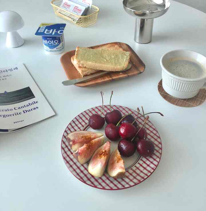 Natural and white tone table setting featuring bread, cherries, figs, yogurt, and coffee cup with a snack atmosphere