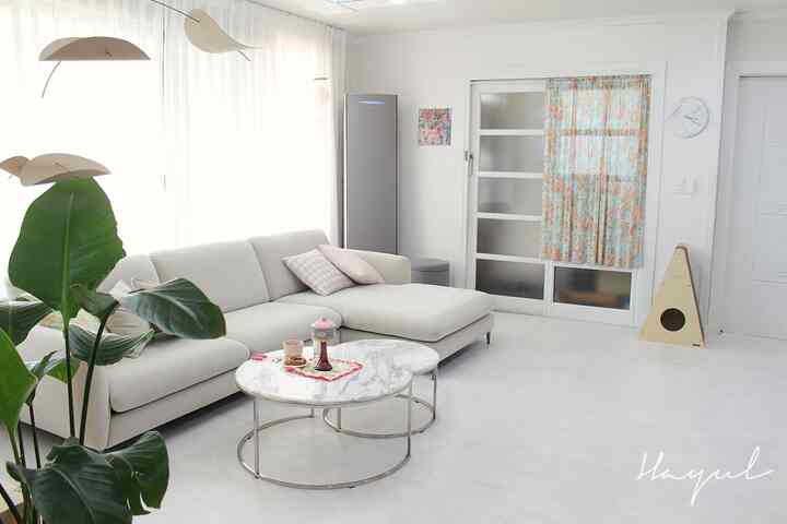 White-toned living room featuring a clean marble round table and a sectional couch, creating a simple and modern space