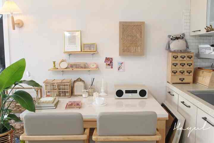 White and natural brown toned home cafe space featuring rattan decor and a large green plant creating cozy workspace