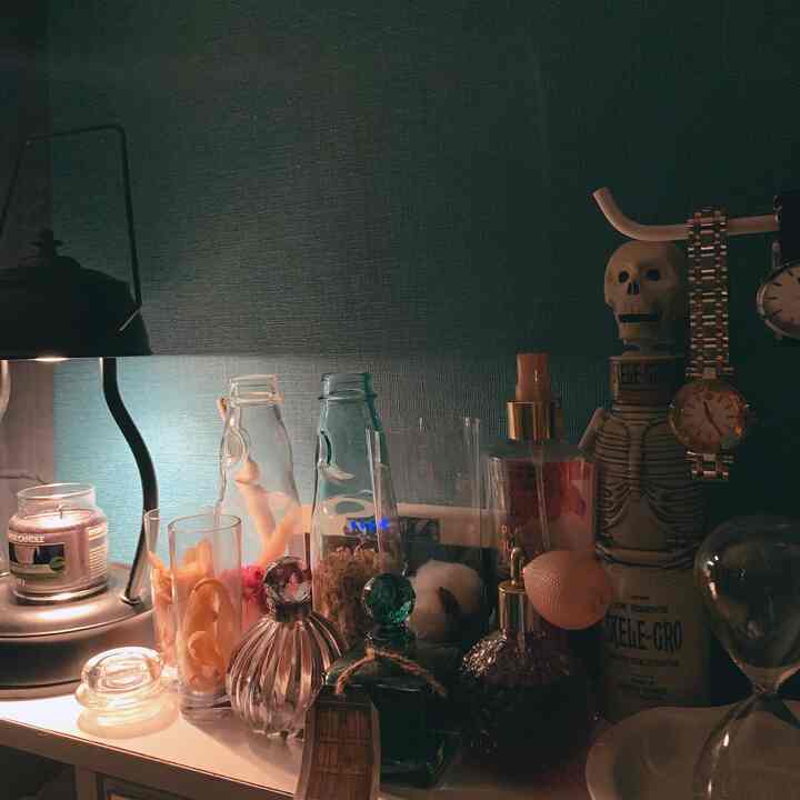 A dark-toned vanity against a navy wall, displaying potion bottles, candle, and skeleton decor creating a magical atmosphere