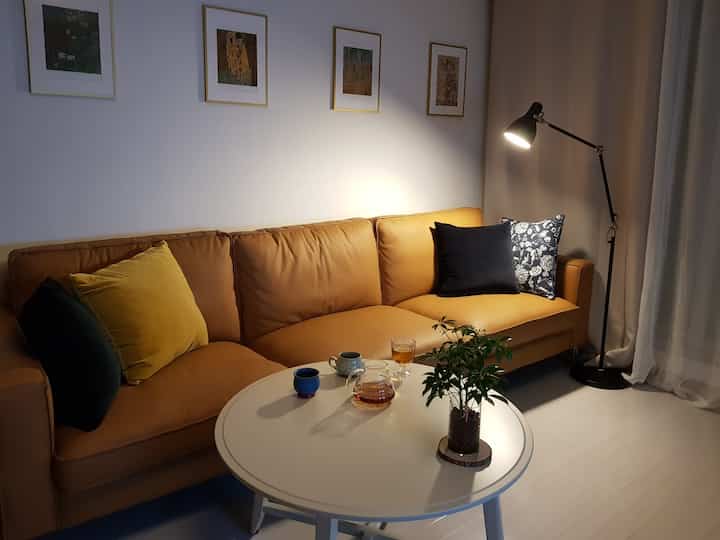 Living room with camel sofa as focal point, featuring a round coffee table and floor lamp creating a warm, simple atmosphere