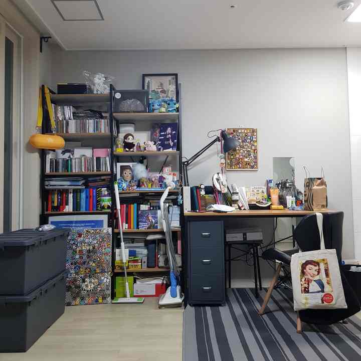 Black and wood tone workspace with desk and bookshelf, cluttered yet warm and personal atmosphere