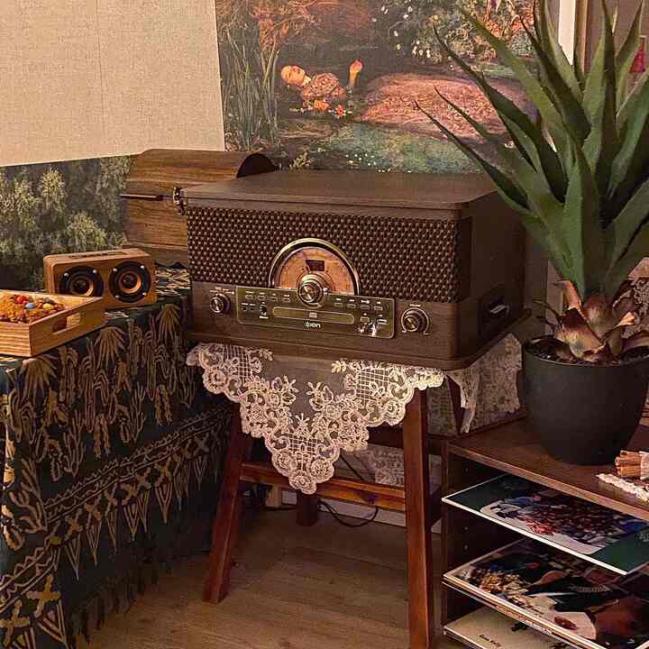 濃い木目調の家具と白いレースが調和した寝室の隅、ヴィンテージのターンテーブルとブルートゥーススピーカーが置かれた落ち着いた雰囲気のインテリア