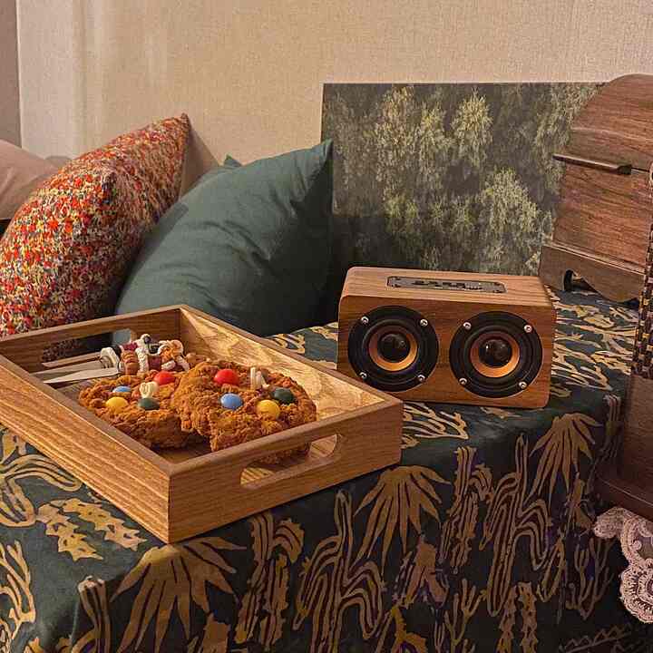 木目調と自然をイメージした絵が配された居心地の良い空間、トレイのクッキーとポータブルブルートゥーススピーカーが置かれたインテリア