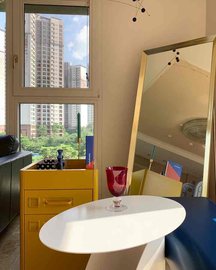 Modern living space with yellow and gold accents, featuring a side table and a full-length mirror