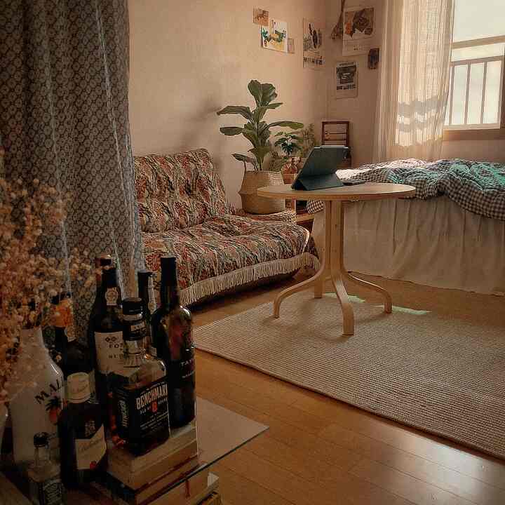 Beige-toned bedroom featuring vintage patterned sofa, round wooden table, and rattan rug creating a cozy atmosphere