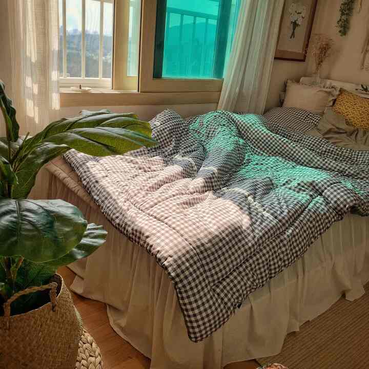 Natural toned bedroom featuring a bed near the window with a rattan plant cover creating a cozy space