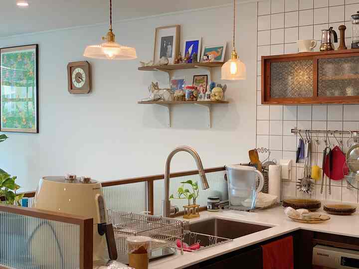 White tiled wall and wood-tone cabinetry blend in a vintage-style kitchen featuring pendant lights and a clean sink area