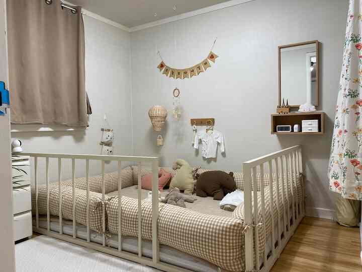 ベージュとナチュラルカラーの子供部屋、中央にチェック柄のバンパーベッドとぬいぐるみが配置された雰囲気のあるインテリア