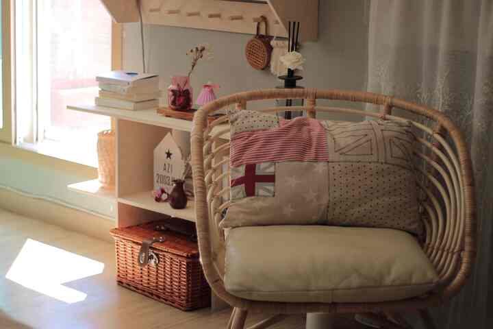 Bright loft bedroom corner featuring a warm brown rattan armchair and white shelving unit with cozy atmosphere