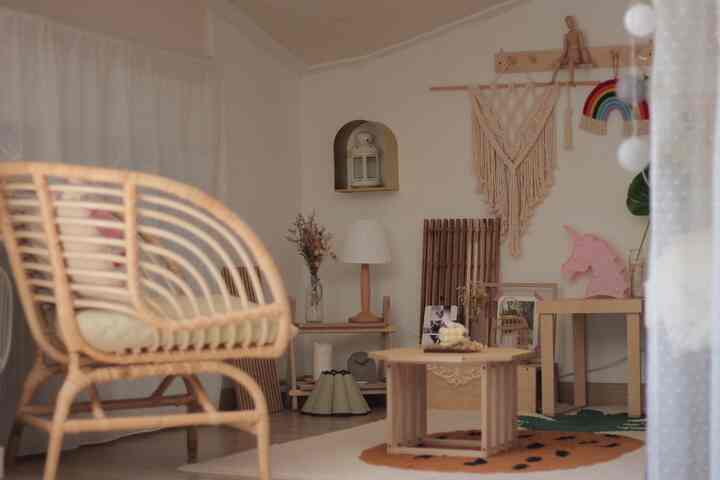 ナチュラルな色調の子供部屋、木目調の家具とラタンチェア、マクラメの装飾が配置された印象的な空間