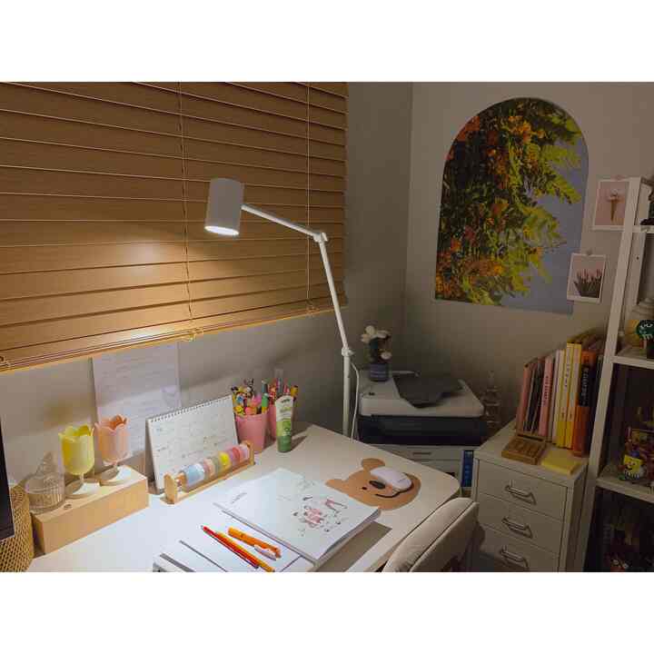 White and wood tone compact study featuring a desk, floor lamp, and storage units, creating a cozy and functional workspace