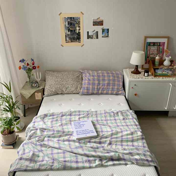 White and light brown toned bedroom featuring mattress, nightstands, framed pictures with a natural cozy interior atmosphere