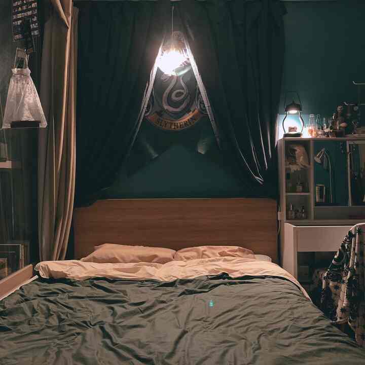 Green and beige toned bedroom featuring a wooden bed with Slytherin banner creating a cozy vibe