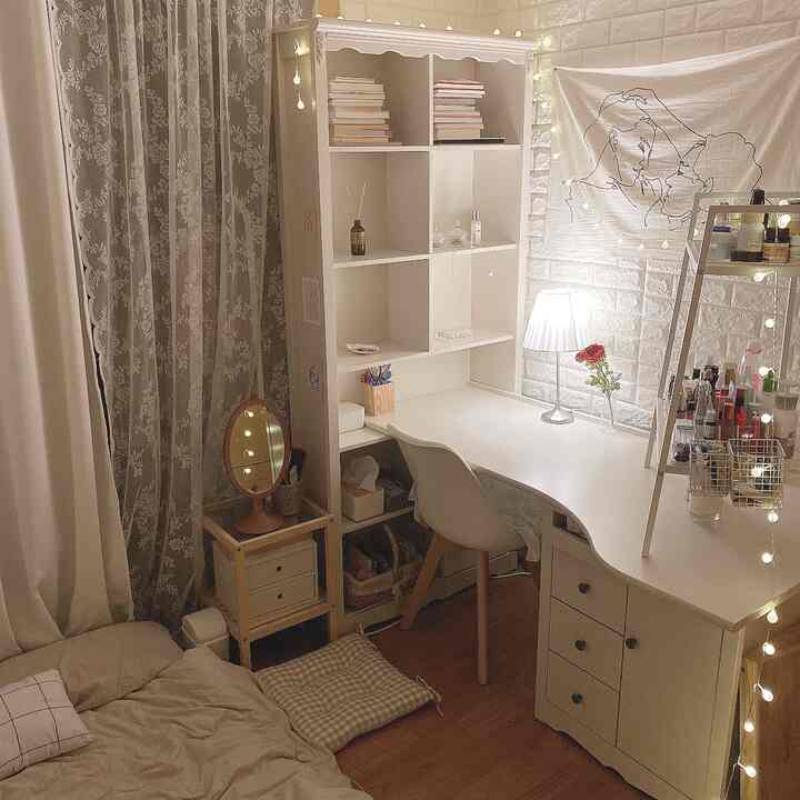 Small bedroom in white and beige tones featuring a white desk, chair, and warm lighting creating a cozy home office space