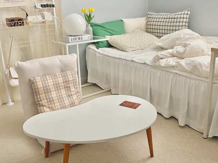 柔らかいナチュラルカラーのリビング、座椅子ソファと曲線的な白いコーヒーテーブルが配置された雰囲気のあるインテリア